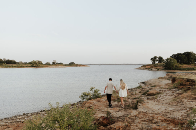 A couple in neutral attire at Grapevine Lake take candid engagement photos.
