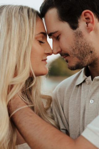 A couple in neutral attire at Grapevine Lake take candid engagement photos.