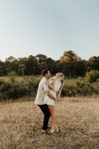 A couple in neutral attire at Grapevine Lake take candid engagement photos.