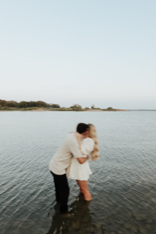 A couple in neutral attire at Grapevine Lake take candid engagement photos.