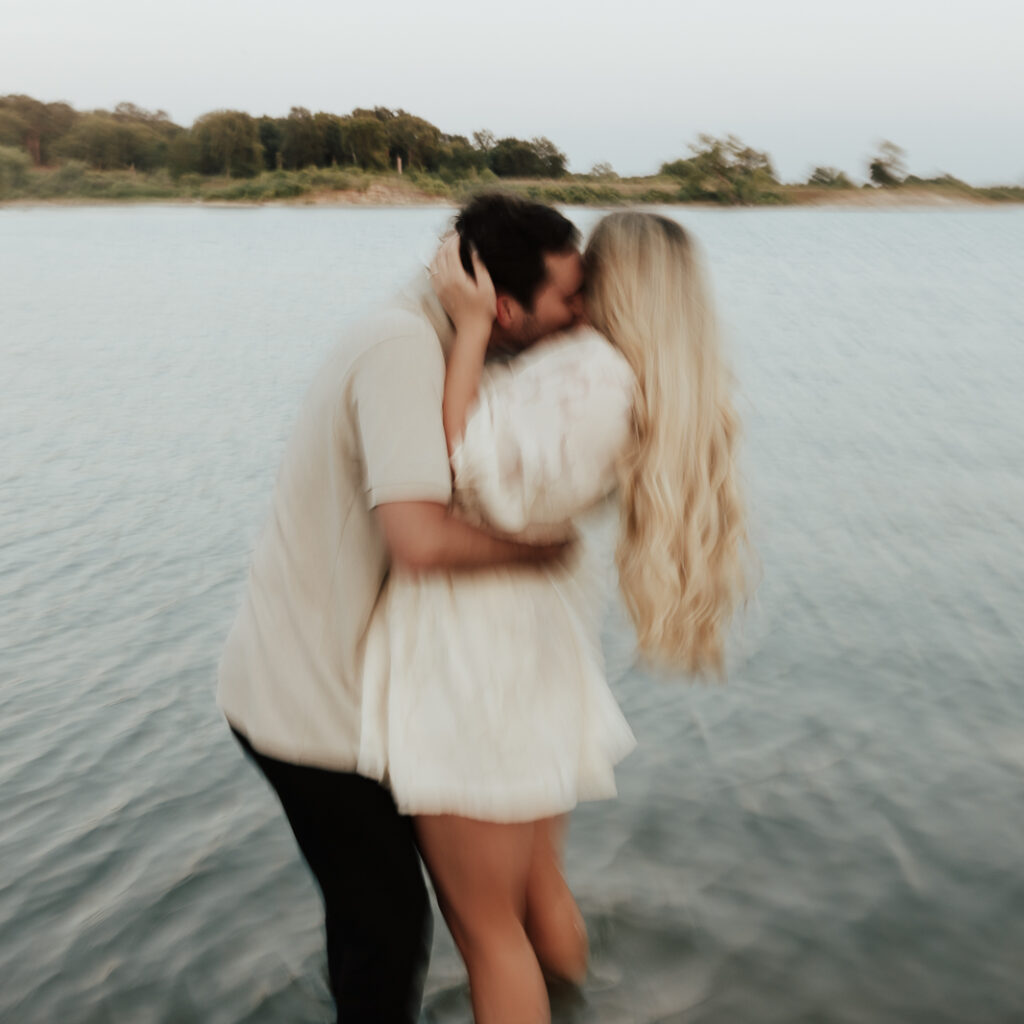A couple in neutral attire at Grapevine Lake take candid engagement photos.