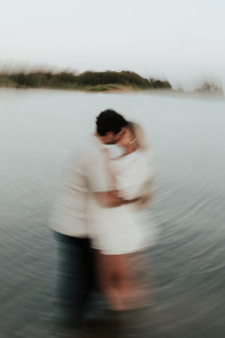 A couple in neutral attire at Grapevine Lake take candid engagement photos.