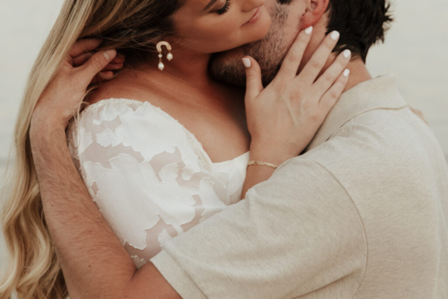 A couple in neutral attire at Grapevine Lake take candid engagement photos.