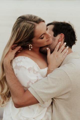 A couple in neutral attire at Grapevine Lake take candid engagement photos.
