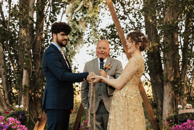 The father of the bride helps complete a celtic knot wedding ceremony at his daughter's micro-wedding