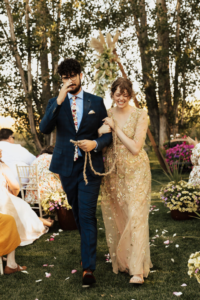 A bride in a gold dress walks down the aisle after being married to her groom