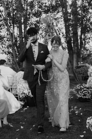 Black and white image of a bride and groom walking down the aisle after being married
