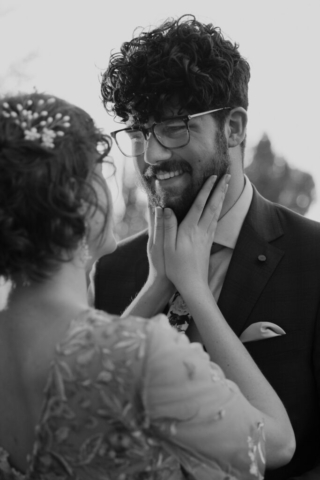 Black and White image of bride in a gold dress holding her groom's face