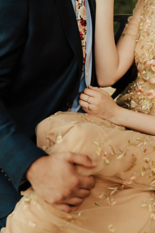 A bride in a gold dress and her groom in a blue suit detail shot