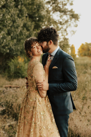 A bride in a gold dress and her groom in a blue suit