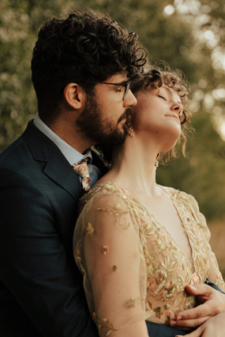 A bride in a gold dress and her groom in a blue suit