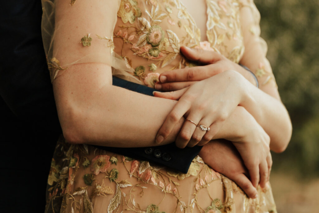 A bride in a gold dress and her groom in a blue suit detail shot