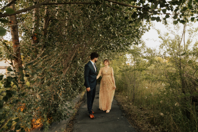 A bride in a gold dress and her groom in a blue suit