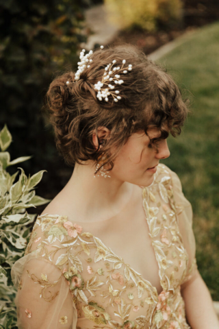 A bride in a gold dress with white pearl headpieces