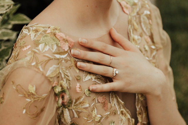 A bride in a gold dress showing her unique geometric wedding ring