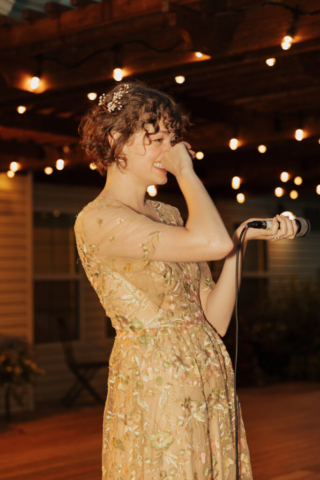 A bride in a gold dress gives her wedding speech