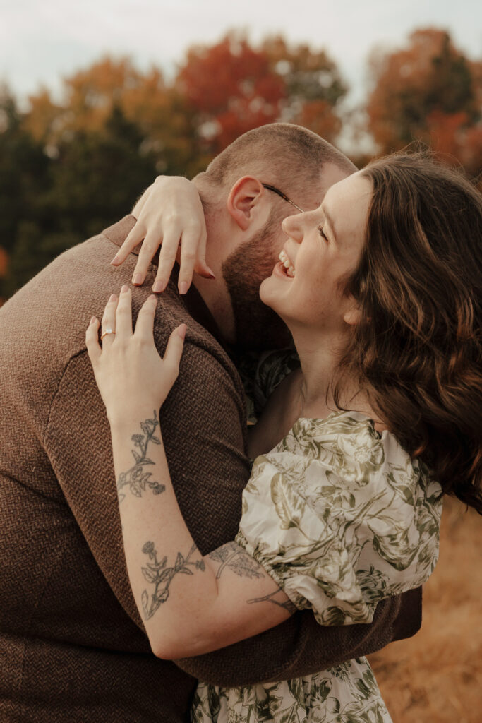 A couple in neutral attire run in an open field take their engagement photos at sunrise by Hannah Lylene Photography.