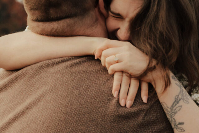 A couple in neutral attire run in an open field take their engagement photos at sunrise by Hannah Lylene Photography.