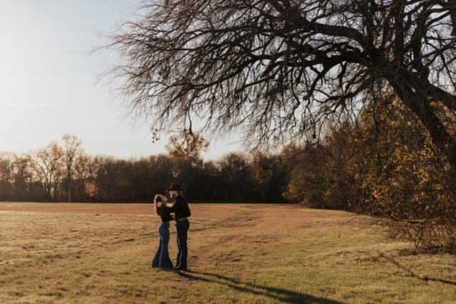 A couple in neutral attire in an open field in Fort Worth, Texas take their documentary style wedding engagement photos.