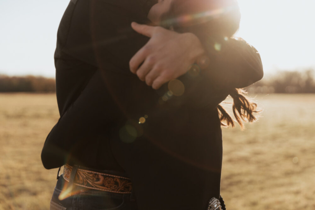 A couple in neutral attire in an open field in Fort Worth, Texas take their documentary style wedding engagement photos.