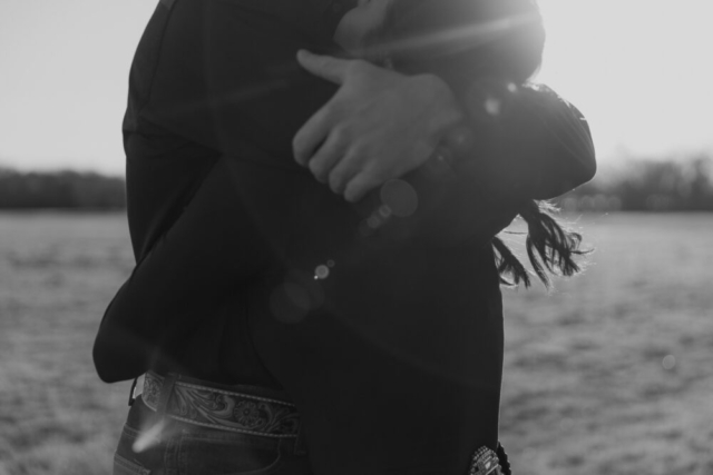 A couple in neutral attire in an open field in Fort Worth, Texas take their documentary style wedding engagement photos.