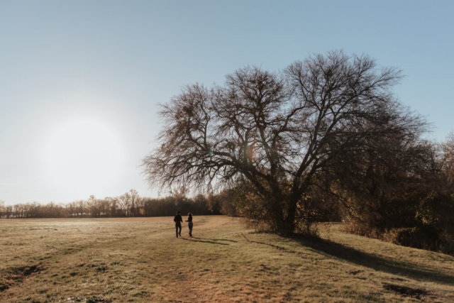 A couple in neutral attire in an open field in Fort Worth, Texas take their documentary style wedding engagement photos.