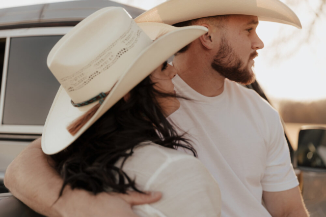 A couple in neutral attire in an open field in Fort Worth, Texas take their documentary style wedding engagement photos.