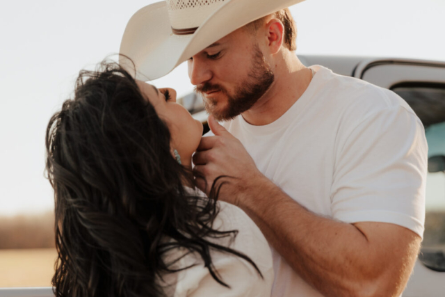 A couple in neutral attire in an open field in Fort Worth, Texas take their documentary style wedding engagement photos.