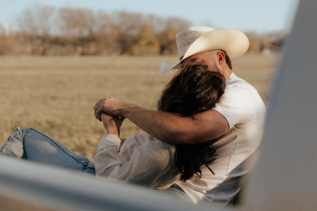 A couple in neutral attire in an open field in Fort Worth, Texas take their documentary style wedding engagement photos.