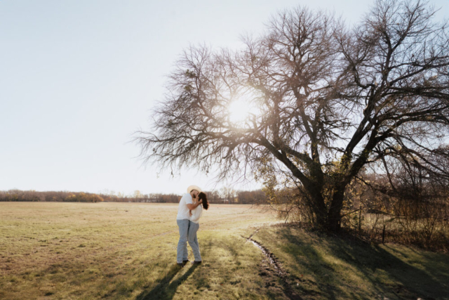 A couple in neutral attire in an open field in Fort Worth, Texas take their documentary style wedding engagement photos.