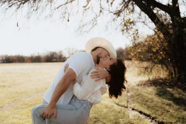 A couple in neutral attire in an open field in Fort Worth, Texas take their documentary style wedding engagement photos.