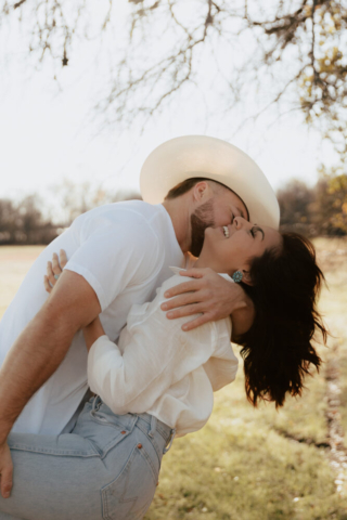 A couple in neutral attire in an open field in Fort Worth, Texas take their documentary style wedding engagement photos.