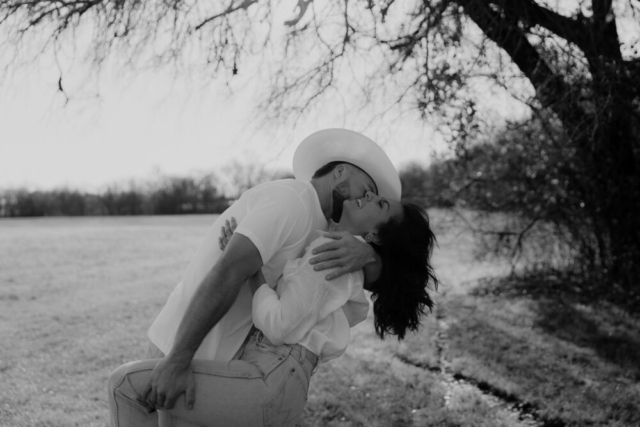 A couple in neutral attire in an open field in Fort Worth, Texas take their documentary style wedding engagement photos.