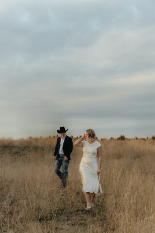 A couple in neutral attire run in an open field take their cinematic and documentary style engagement photos by Hannah Lylene Photography.
