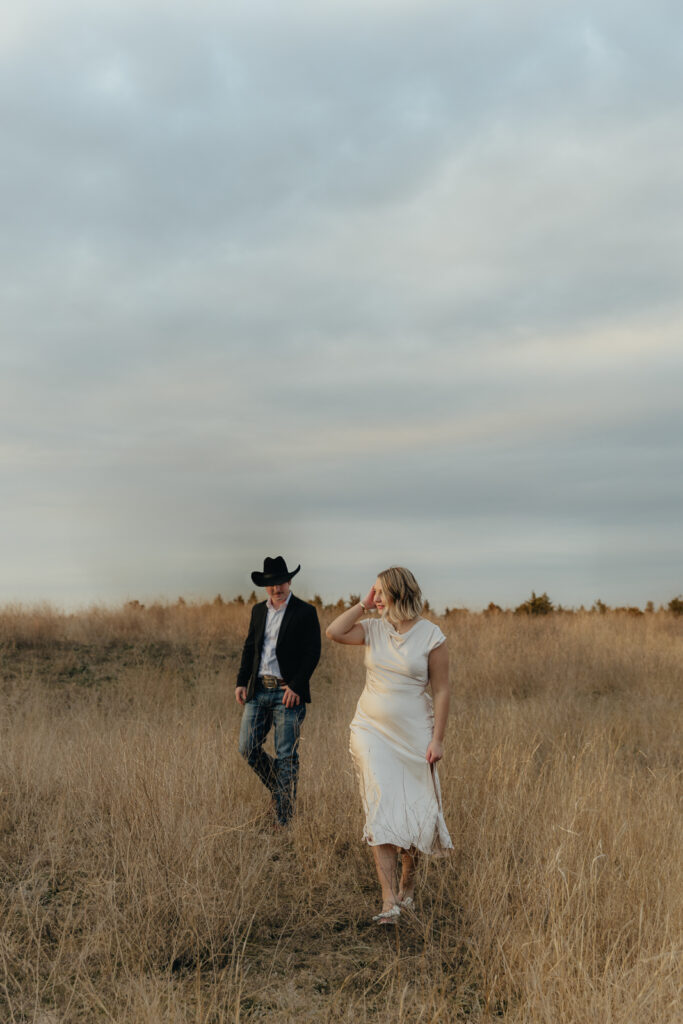 A couple in neutral attire run in an open field take their cinematic and documentary style engagement photos by Hannah Lylene Photography.