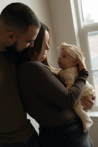 A young couple holds their newborn baby in their nursery to take intimate family photos in Dallas, Texas.