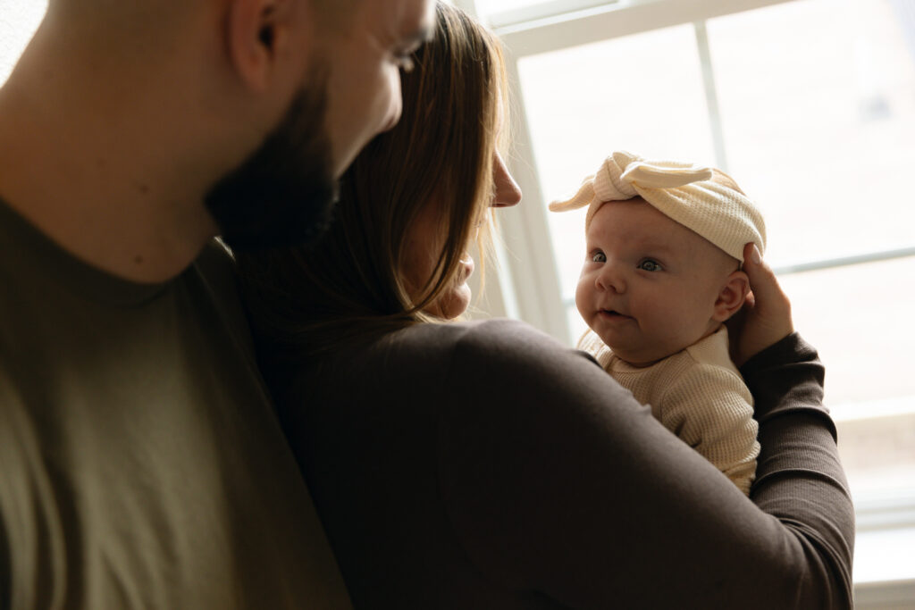 A young couple holds their newborn baby in their nursery to take intimate family photos in Dallas, Texas.