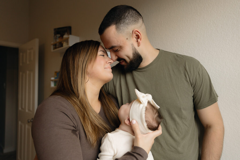 A young couple holds their newborn baby in their nursery to take intimate family photos in Dallas, Texas.