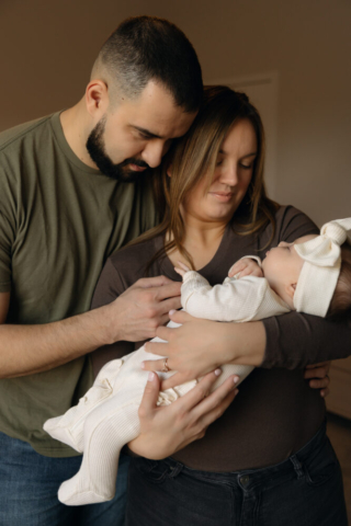 A young couple holds their newborn baby in their nursery to take intimate family photos in Dallas, Texas.