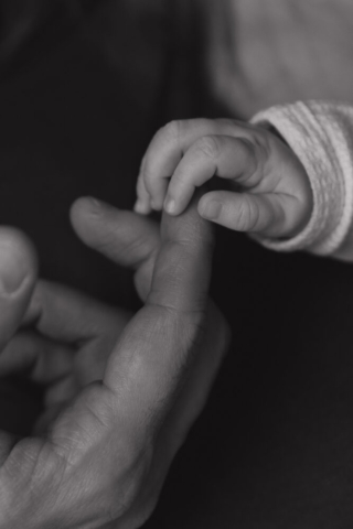 A young couple holds their newborn baby in their nursery to take intimate family photos in Dallas, Texas.