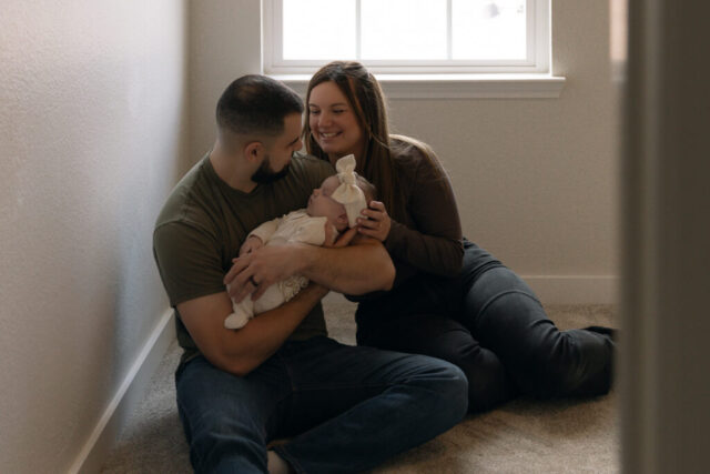 cinematic-family-photographer A young couple holds their newborn baby in their nursery to take intimate family photos in Dallas, Texas.