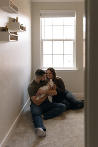 A young couple holds their newborn baby in their nursery to take intimate family photos in Dallas, Texas.