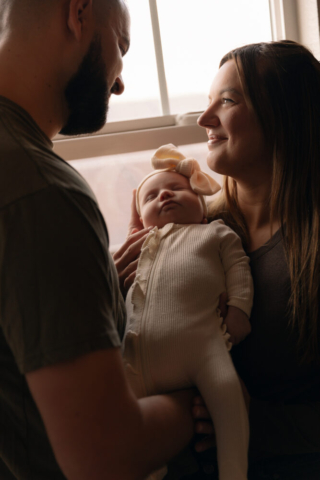 A young couple holds their newborn baby in their nursery to take intimate family photos in Dallas, Texas.