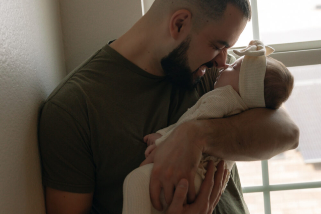 A young couple holds their newborn baby in their nursery to take intimate family photos in Dallas, Texas.