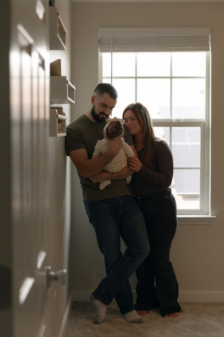 A young couple holds their newborn baby in their nursery to take intimate family photos in Dallas, Texas.