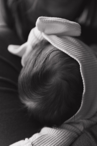 A young couple holds their newborn baby in their nursery to take intimate family photos in Dallas, Texas.