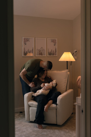 A young couple holds their newborn baby in their nursery to take intimate family photos in Dallas, Texas.