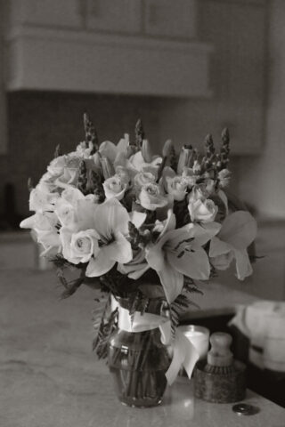 Simple, white flowers line the base of a white flower arch in a modern white aesthetic home for a wedding ceremony. Timeless indoor wedding in Dallas, captured with a refined, editorial approach by DFW documentary wedding photographer.
