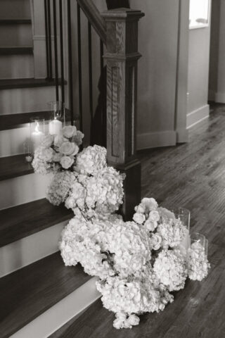 Simple, white flowers line the base of stairs in a modern white aesthetic home for a wedding ceremony. Timeless indoor wedding in Dallas, captured with a refined, editorial approach by DFW documentary wedding photographer.