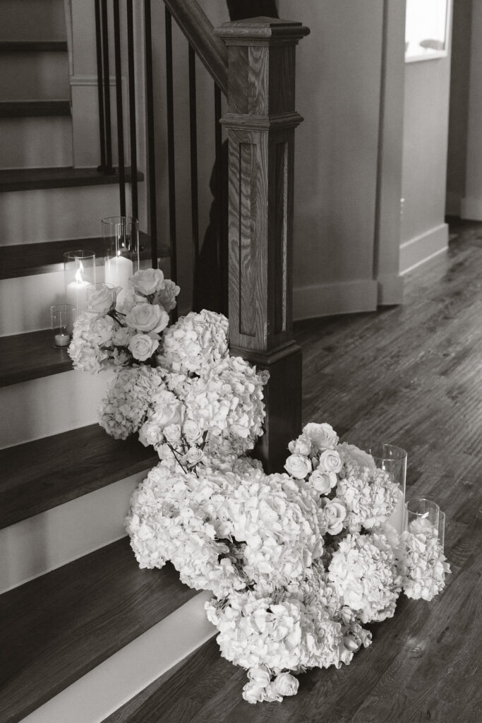 Simple, white flowers line the base of stairs in a modern white aesthetic home for a wedding ceremony. Timeless indoor wedding in Dallas, captured with a refined, editorial approach by DFW documentary wedding photographer.